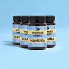 Four jars of Wonder Honey Manuka honey on a blue background