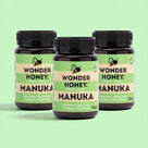 Three jars of Wonder Honey Manuka honey on a light green background