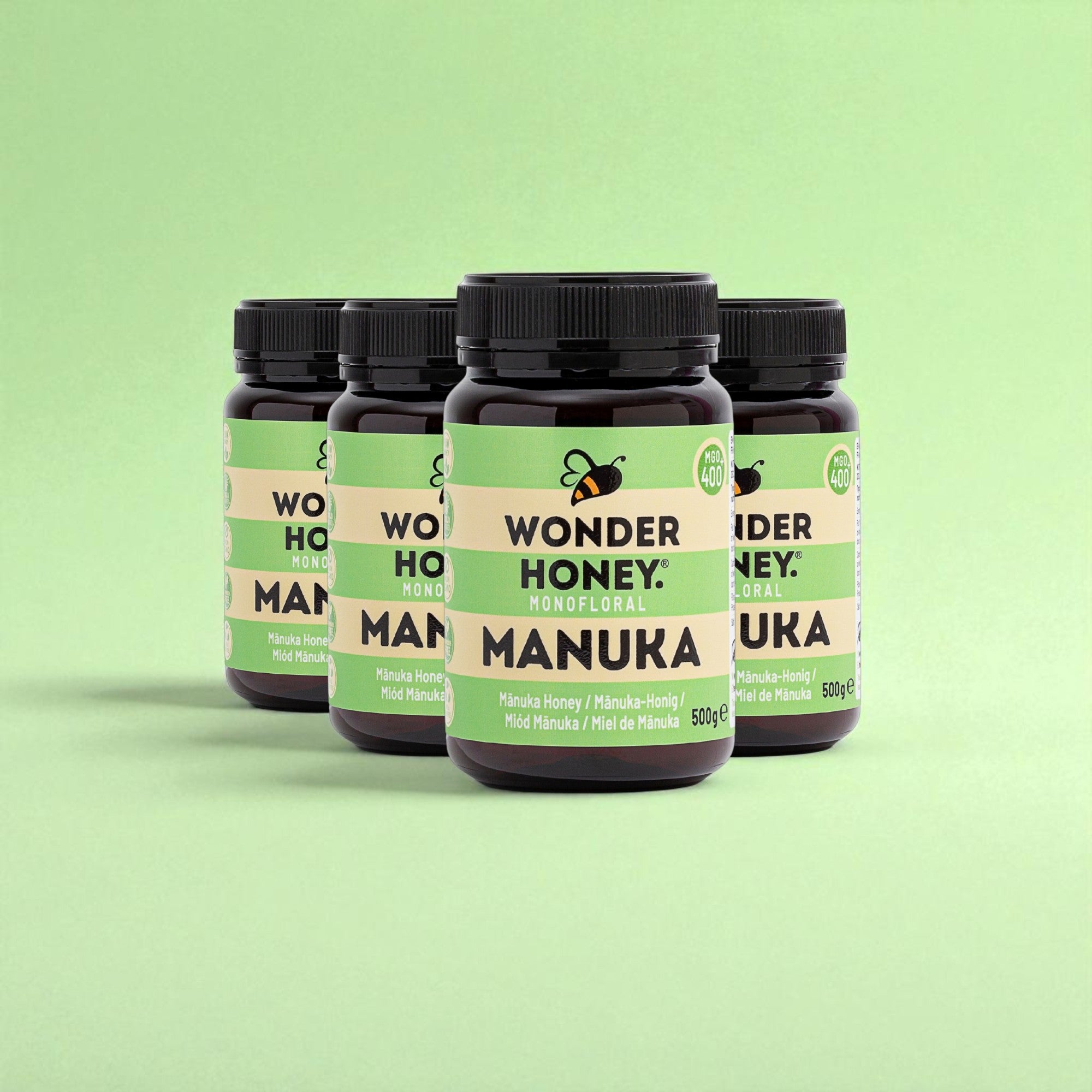 Four bottles of Wonder Honey Manuka honey on a light green background