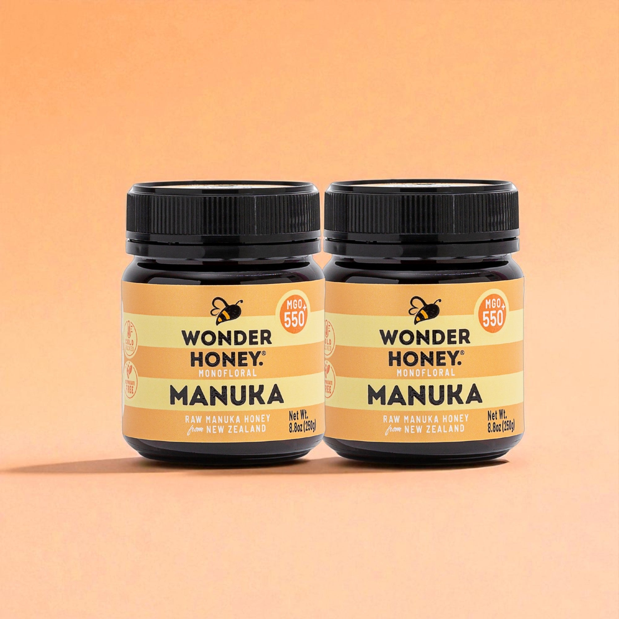 Two jars of Wonder Honey Manuka honey on a peach background