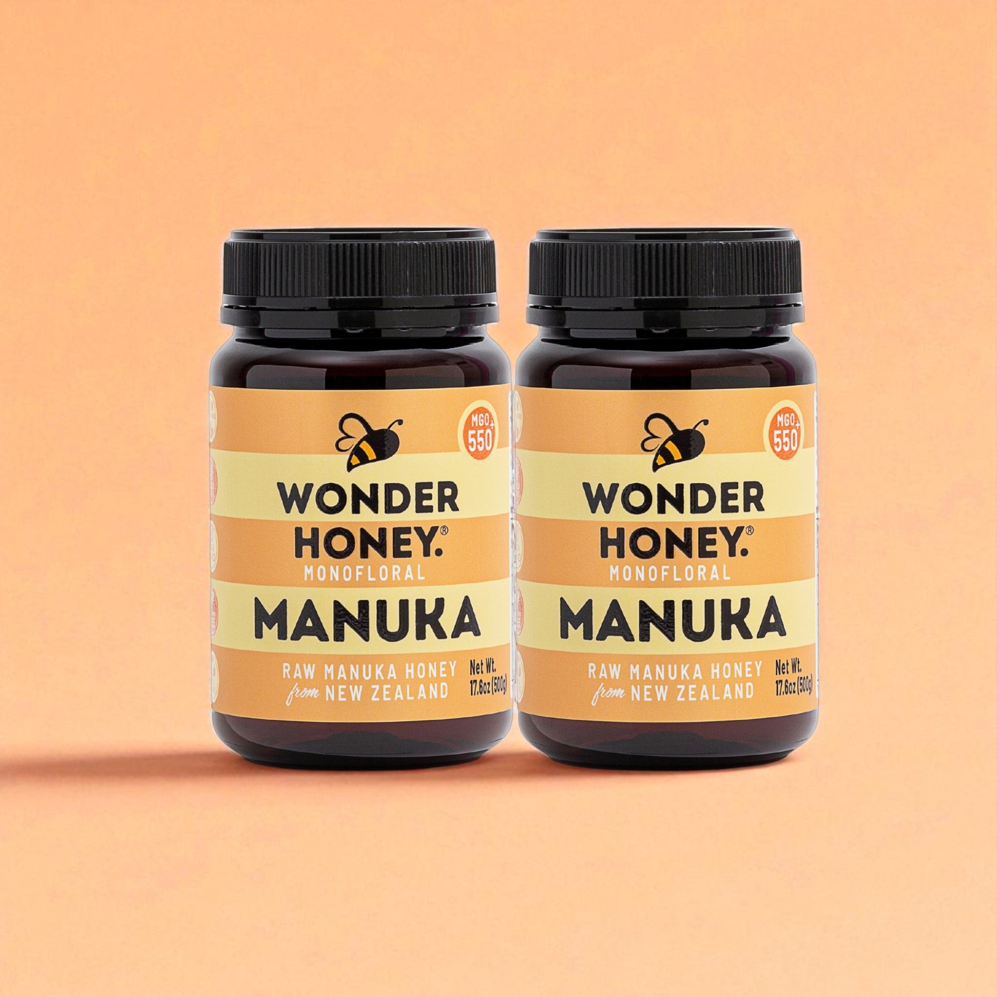 Two bottles of Wonder Honey Manuka honey on a peach background