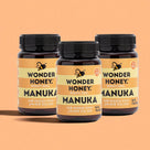 Three bottles of Wonder Honey Manuka honey on an orange background