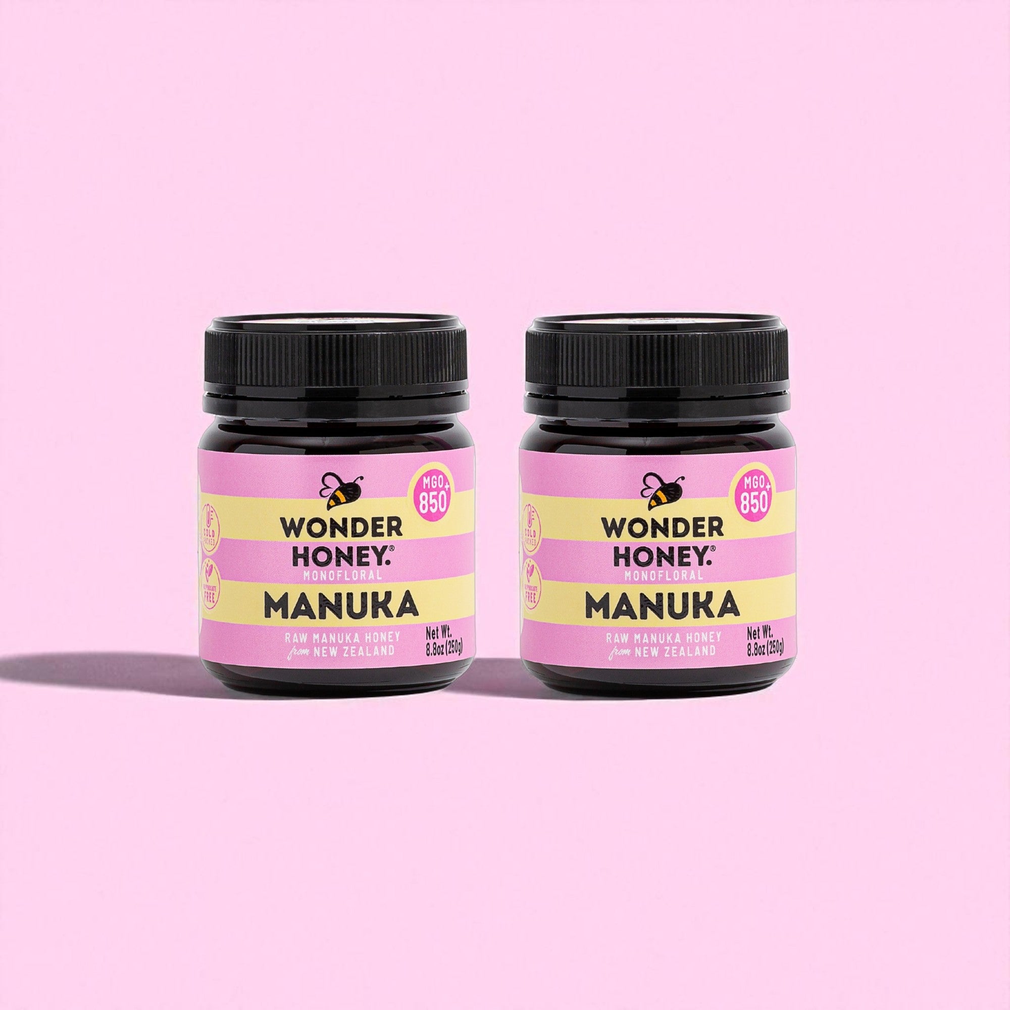 Two jars of Wonder Honey Manuka honey on a pink background