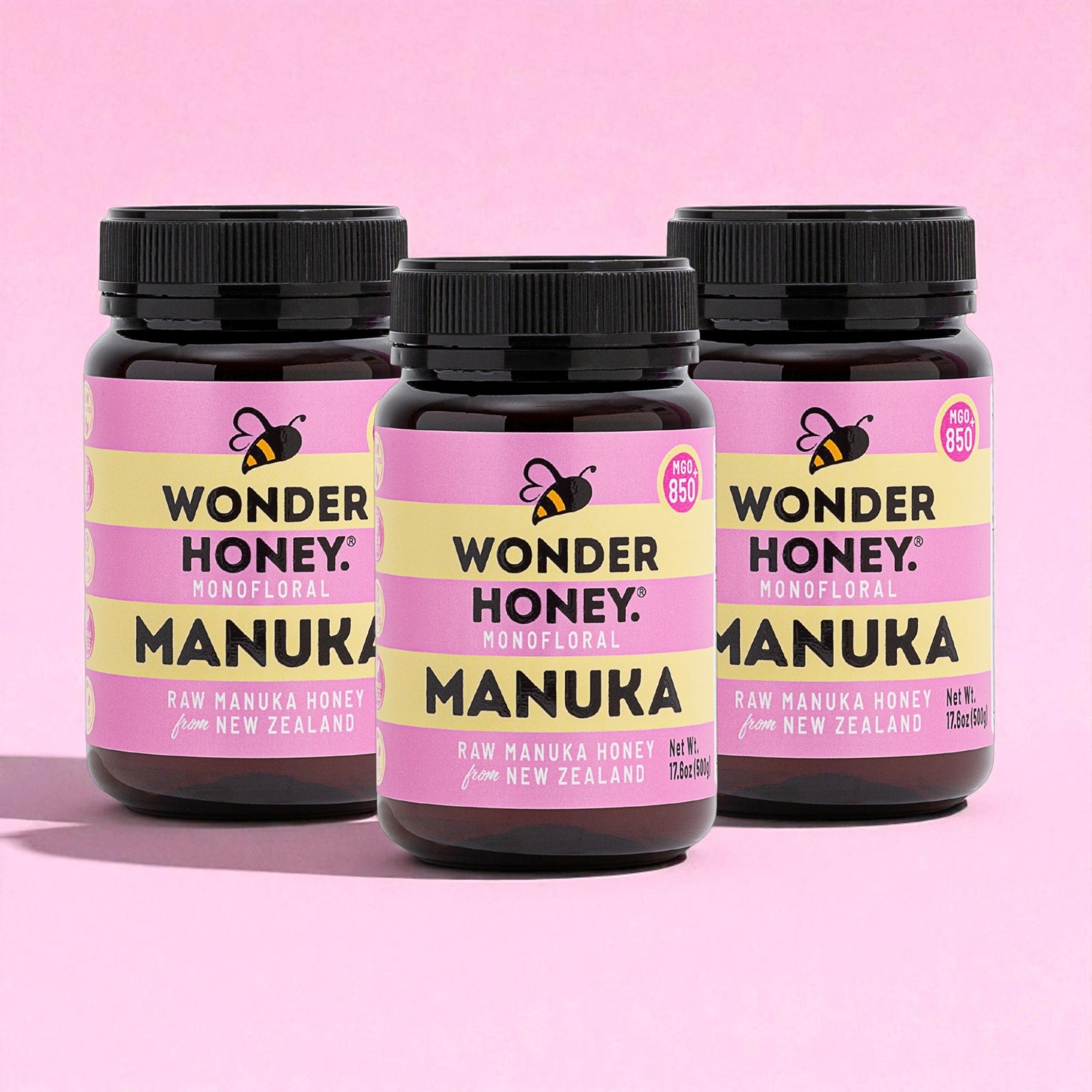 Three bottles of Wonder Honey Manuka honey on a pink background