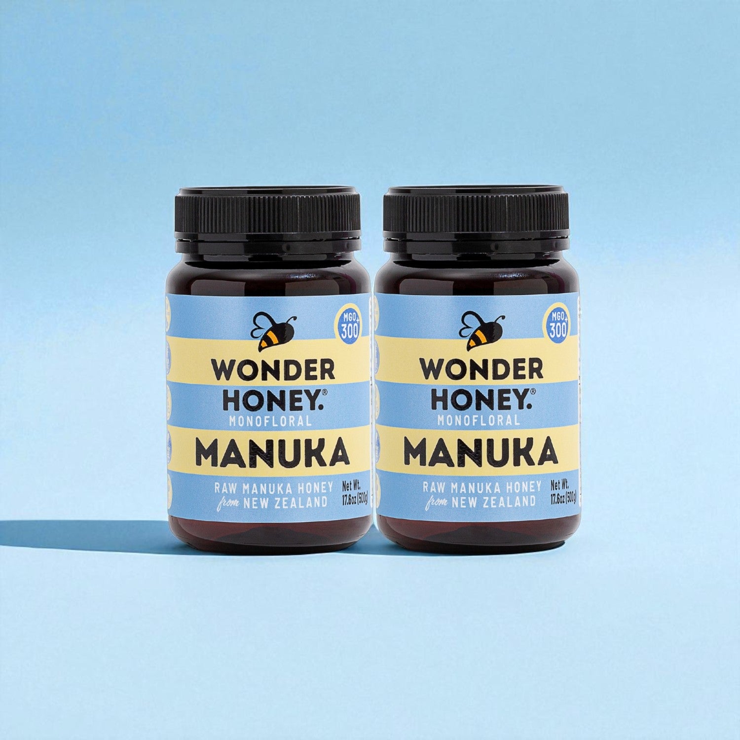 Two bottles of Wonder Honey Manuka honey on a light blue background